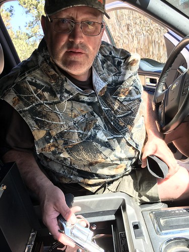 Man showing his gun from a car console safe