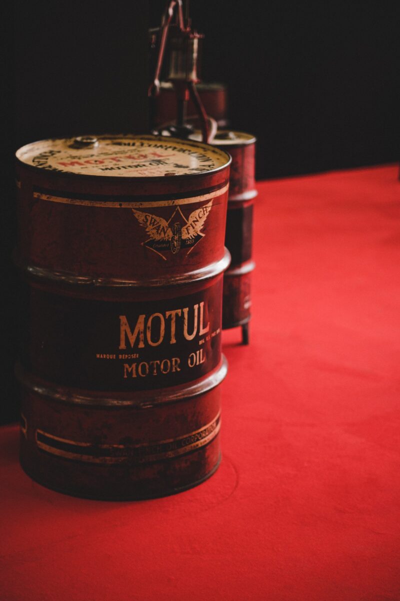 Barrels of motor oil in red cans placed on red flooring in a factory