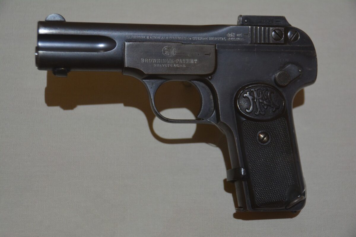 A close-up black pistol handgun placed on a white surface